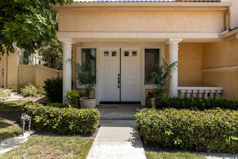 Covered front entry with columns and double doors framed by mature hedging at 5353 Renaissance Ave San Diego