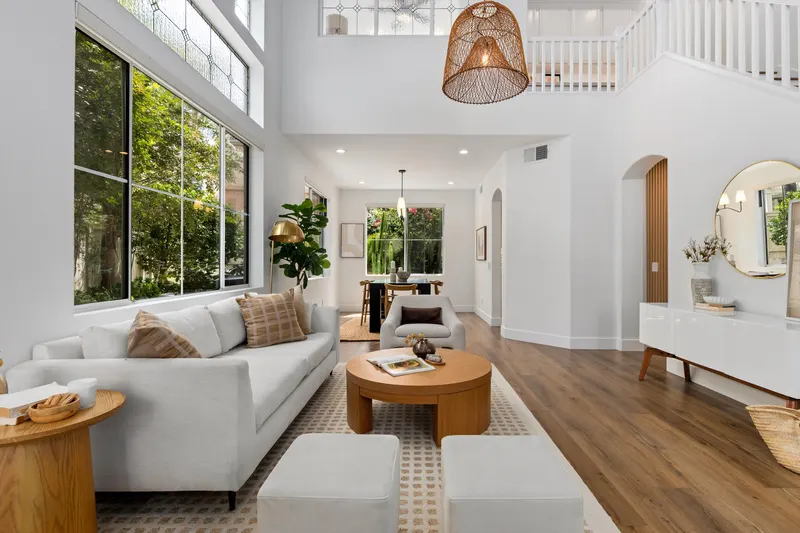 Living room with two-story vaulted ceiling, oversized windows and woven pendant light at 5353 Renaissance Ave San Diego