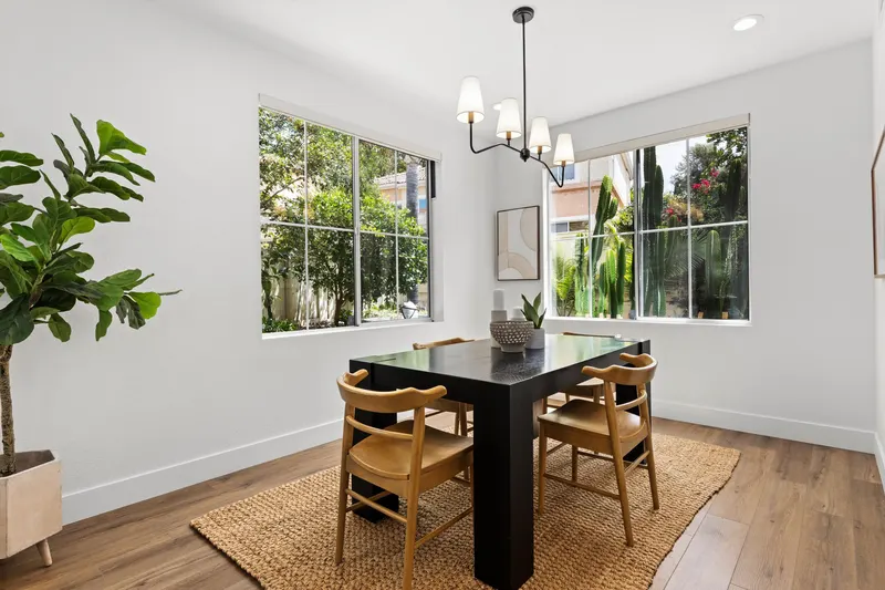 Formal dining room with black table, brass chandelier and garden-view windows at 5353 Renaissance Ave San Diego