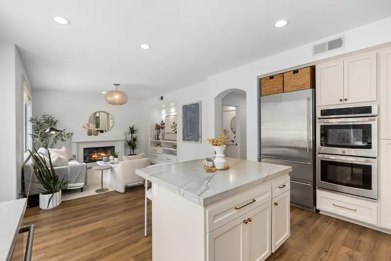 Kitchen island looking into the family room with built-in shelving and fireplace at 5353 Renaissance Ave San Diego