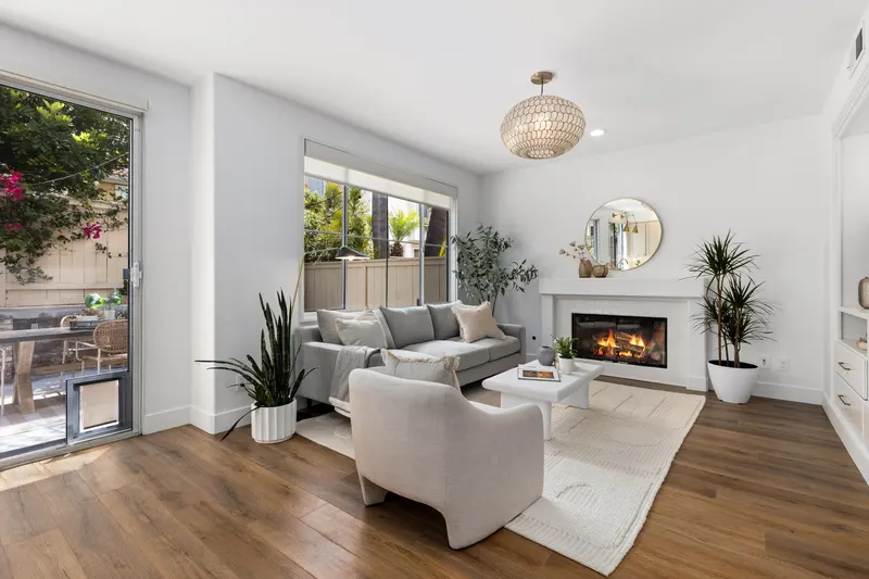 Family room with lit fireplace, sliding doors to the patio and bougainvillea beyond at 5353 Renaissance Ave San Diego