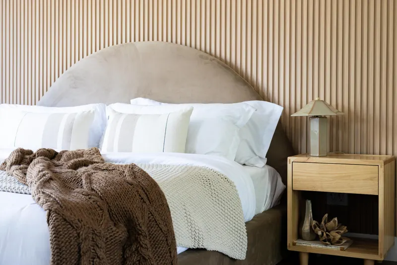 Primary bedroom bedding detail against the fluted wood accent wall at 5353 Renaissance Ave San Diego