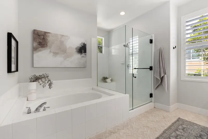 Renovated primary bathroom with soaking tub and frameless glass shower at 5353 Renaissance Ave San Diego