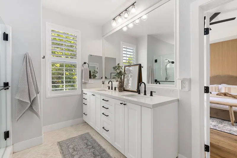 Primary bathroom dual vanity with quartz counter and matte black fixtures at 5353 Renaissance Ave San Diego