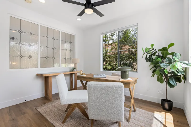 Secondary bedroom staged as a home office with leaded glass window at 5353 Renaissance Ave San Diego