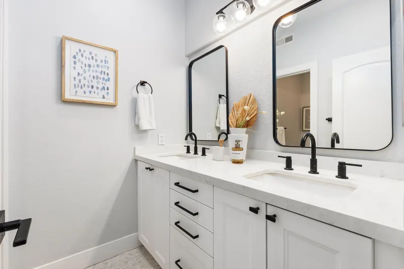Secondary bathroom with dual sinks, black fixtures and framed mirrors at 5353 Renaissance Ave San Diego