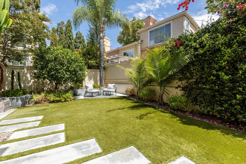 Backyard lawn with concrete paver stepping stones, palms and mature landscaping at 5353 Renaissance Ave San Diego