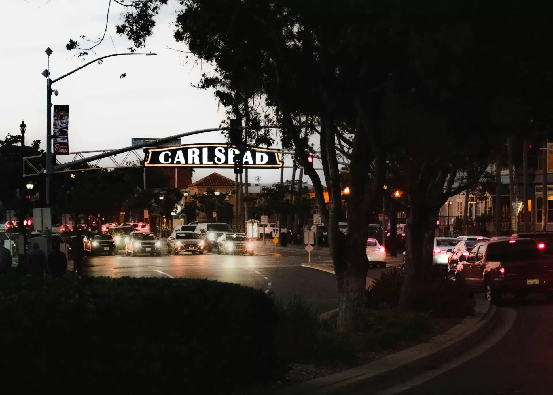 The Carlsbad Village sign over Carlsbad Village Drive at dusk