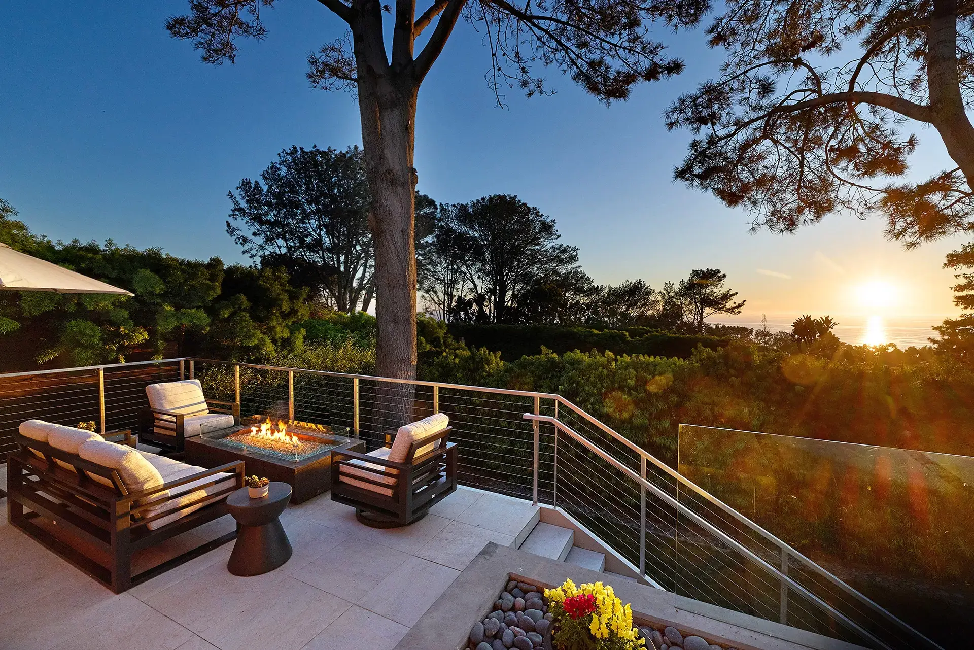 Outdoor deck with fire pit and seating overlooking Pacific Ocean sunset through Torrey Pines at 116 Nob Ave Del Mar listed by Kelli Miller Compass