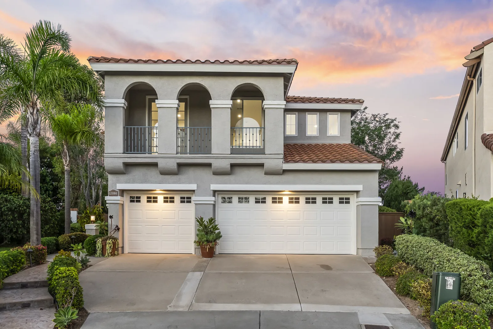 Front exterior at twilight with arched second-story balcony and three-car garage at 12086 Little Silver Ct, Scripps Ranch, San Diego