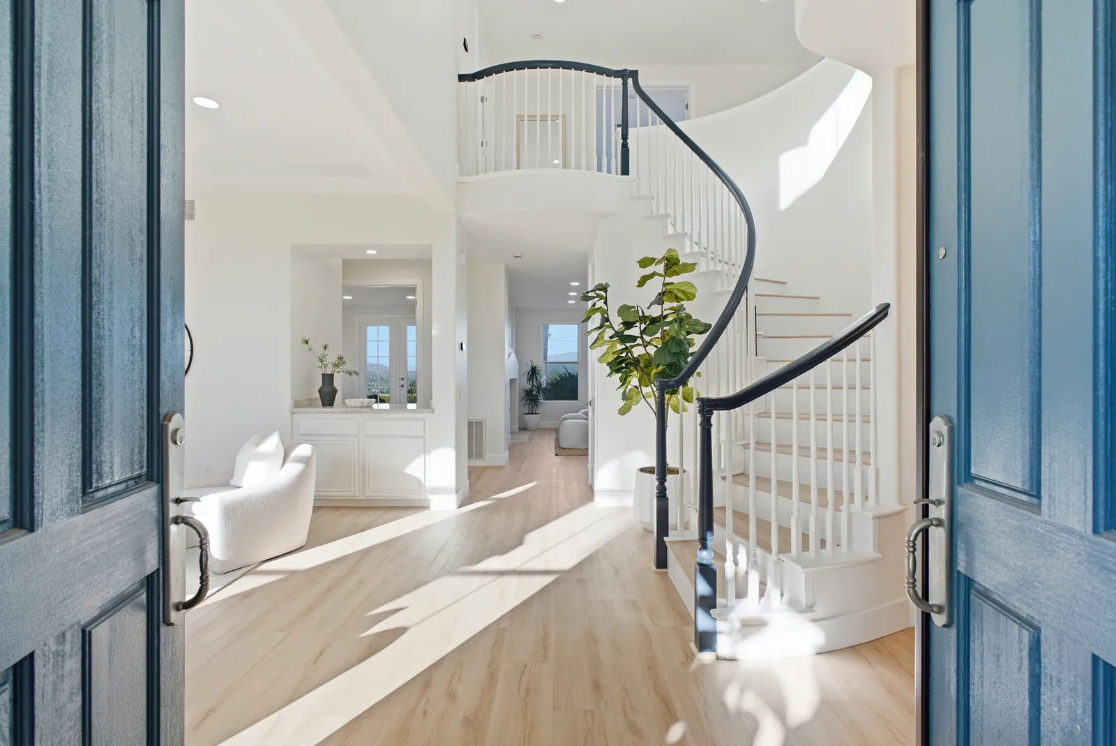 Entry foyer seen through the front doors, with a curved staircase and wood-look flooring at 12086 Little Silver Ct, Scripps Ranch, San Diego