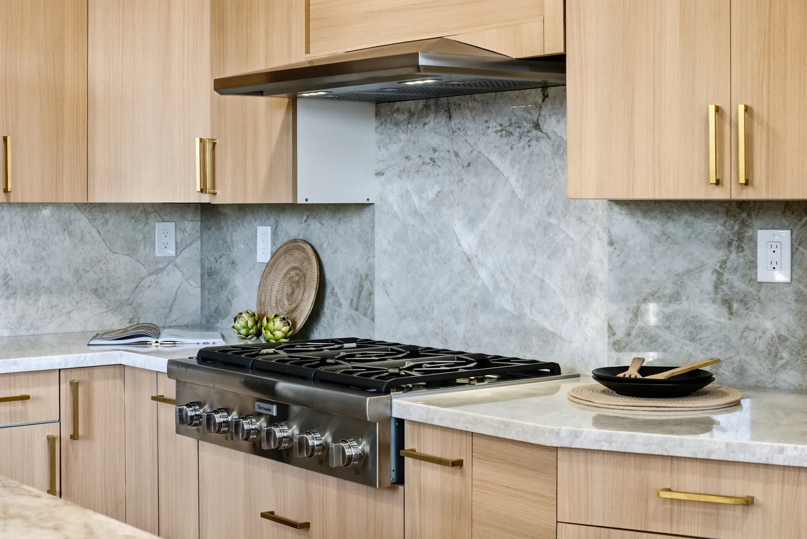 Thermador gas rangetop with a Taj Mahal quartzite backsplash and brass cabinet pulls at 12086 Little Silver Ct, Scripps Ranch, San Diego