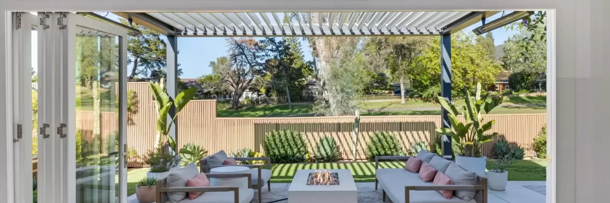 Experience the pinnacle of Southern California’s signature indoor-outdoor lifestyle. The main living space opens completely via 13-foot, 4-panel custom LaCantina accordion doors to reveal a private, ultra-modern entertainer's paradise. A massive 17’ x 14’ premium aluminum pergola with smart articulating louvers lets you dial in the perfect balance of sun and shade over a sleek concrete patio pad. Anchored by a contemporary fire table surrounded by stylish outdoor lounge seating, this meticulously designed backyard is framed by premium modern fencing and opens up to expansive, serene green views of the golf course beyond.