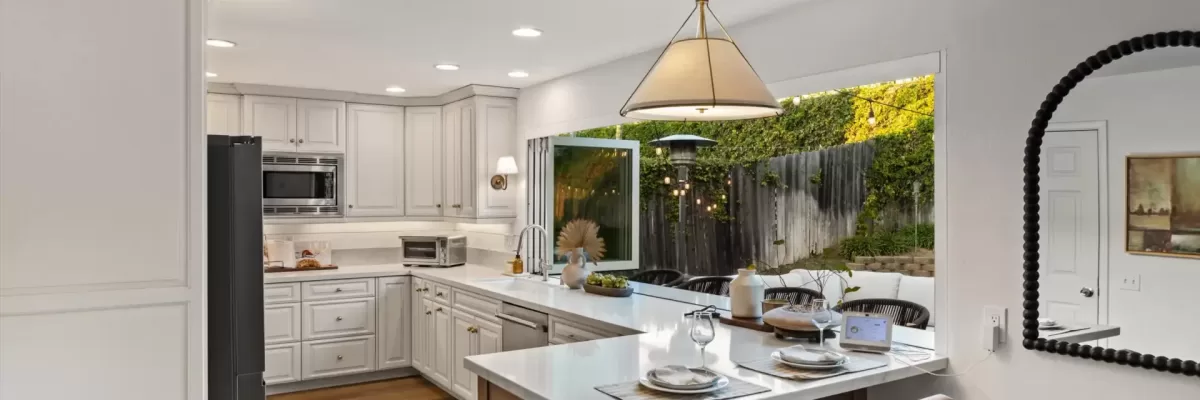 Kitchen with white cabinets and hardwood floors. An accordion window opens to the outside